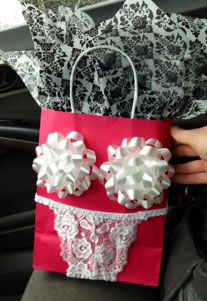 a hand holding a red paper bag with white lace on it