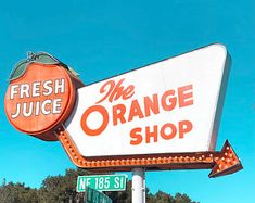 the orange shop sign has an arrow pointing up to it's right side and is advertising fresh juice