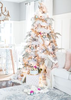 a white christmas tree in the corner of a living room with pink and silver decorations