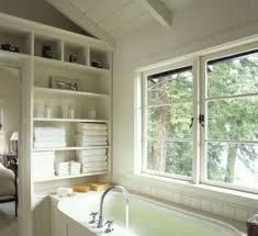 a large bath tub sitting under a window next to a book shelf filled with books