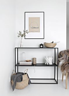 a shelf with baskets and other items on it in a room that has white walls