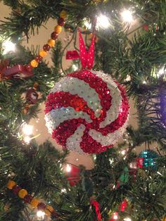 a christmas ornament hanging from the top of a tree with lights on it