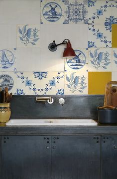 a kitchen with blue and white tiles on the wall, sink and faucet