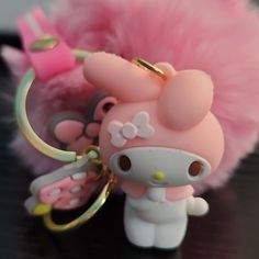 a hello kitty keychain with a pink fluffy ball on it's back