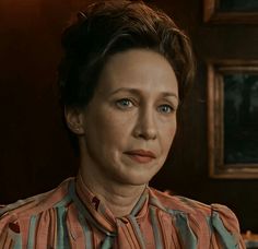 a woman with short hair wearing a striped shirt and looking at the camera while sitting down