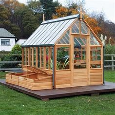 a small wooden greenhouse sitting on top of a lush green field