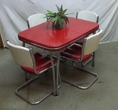 a red table with white chairs and a plant on top