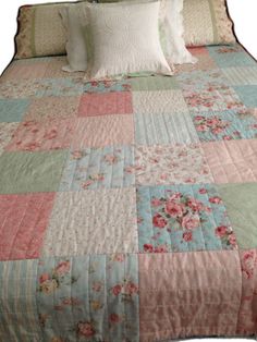 a bed with pink and blue quilts on it's headboard is shown