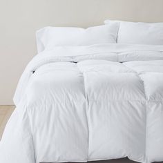 a bed with white sheets and pillows on it