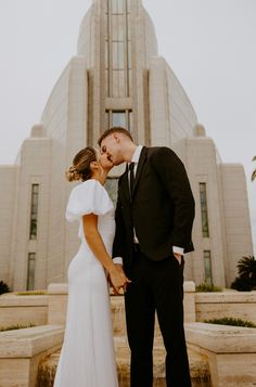 a bride and groom kissing in front of the temple