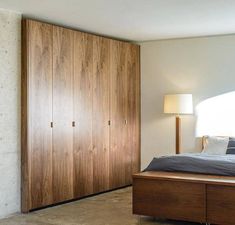 a bedroom with a large bed and wooden closets in the wall next to it