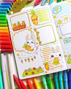 an open planner book with markers and pens on the table in front of it, surrounded by other colorful crayons