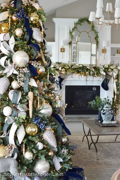 a decorated christmas tree in a living room with blue and gold ornaments on the top