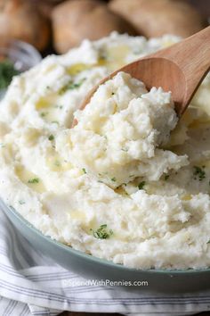 mashed potatoes in a bowl with a wooden spoon and parsley on the side