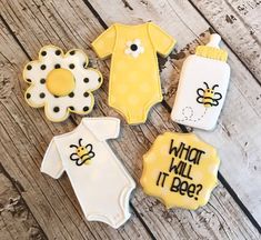 baby shower cookies decorated with bodysuits and onesuits on a wooden table