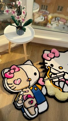 two hello kitty rugs sitting on the floor in front of a window with flowers