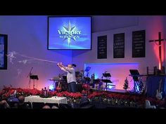 a man standing on top of a stage in front of a cross and other people