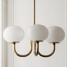 three white lamps hanging from a brass chandelier