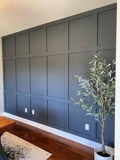 a living room with dark gray paneling and a potted plant