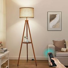 a person is holding a remote control in front of a living room with a lamp