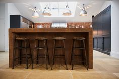 three stools are sitting at the bar in this modern style kitchen with brick walls