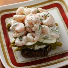 a white plate topped with shrimp and asparagus on top of a piece of bread