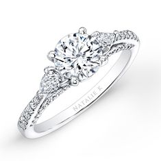 a white gold engagement ring with two diamonds on the side and an intricate band around it