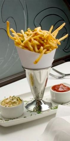 french fries on a plate with dipping sauces in a glass bowl next to it