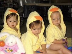 three children sitting on the floor in matching yellow bathrobes and holding stuffed animals