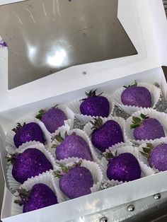 a white box filled with purple chocolate covered strawberries