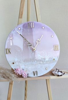 a pink clock sitting on top of a wooden shelf