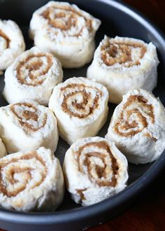 a pan filled with cinnamon rolls on top of a wooden table