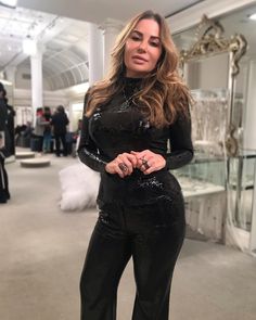 a woman in black sequin jumpsuits posing for the camera with her hands on her hips