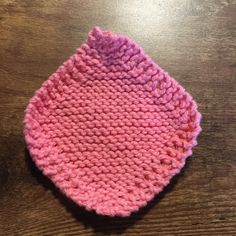 a pink knitted hat sitting on top of a wooden table