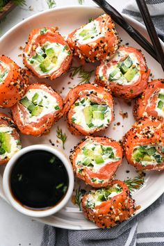 a white plate topped with sushi rolls and dipping sauce