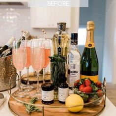 champagne and strawberries on a tray in the kitchen with bottles of wine, lemons, rosemary, and other condiments