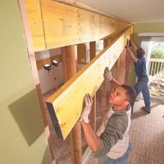 two men are working on the framing of a house with wood flooring and walls