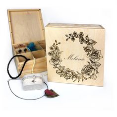 an open wooden box with jewelry inside and flowers on the lid, along with other items