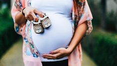 a pregnant woman holding her baby shoes