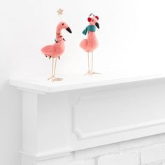 two flamingos are standing on top of a fireplace mantel, one is pink and the other is blue