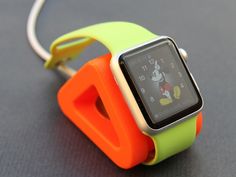 an orange and green apple watch with mickey mouse on the face is attached to a white cord