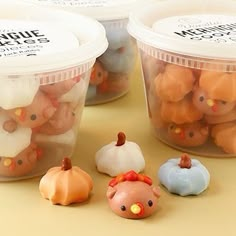 several plastic containers filled with little pumpkins and small figurines on a table