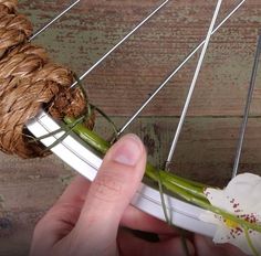 a hand is holding a flower that has been attached to the spokes of a bicycle wheel