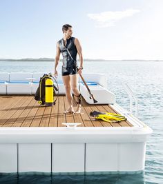 a man standing on top of a boat holding a yellow life jacket and snorkel