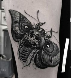 a black and white image of a moth on the thigh with skulls in its eyes