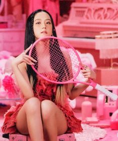 a woman sitting on the ground holding a tennis racquet in her hand and wearing a red dress