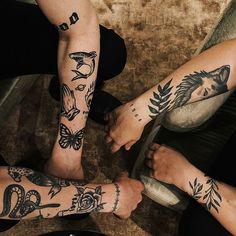 three people with tattoos on their arms and legs sitting next to each other in a circle