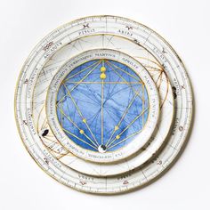 two white and blue plates with gold lines on them, each containing an image of the sun