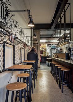 the interior of a restaurant with wooden stools and bar tables in front of it