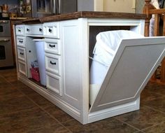 an open cabinet in the middle of a kitchen floor that is being used as a trash can